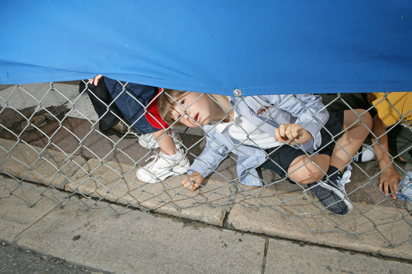 A young fan peeks under the fence to watch the action