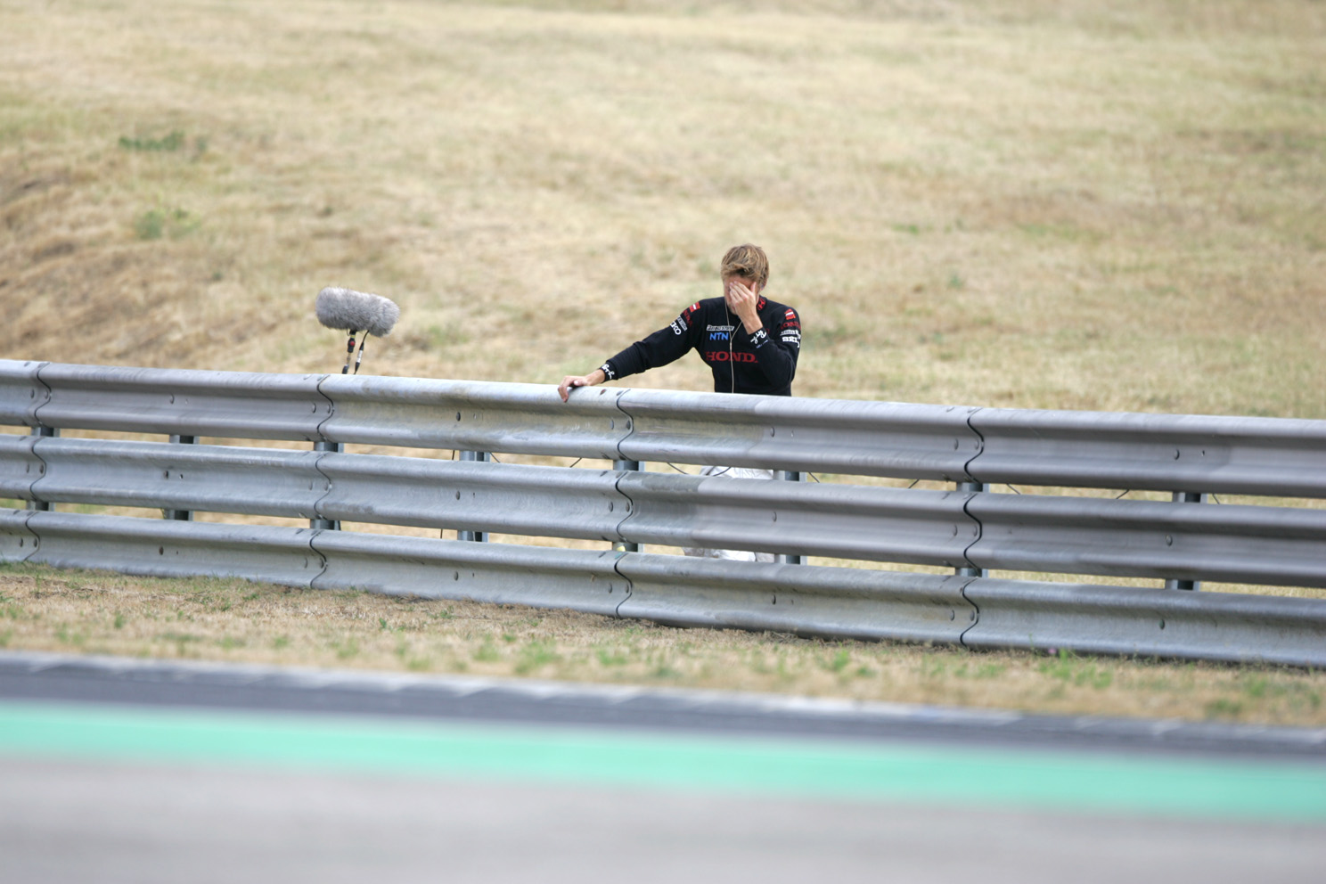 Jenson Button watches the rest of the race from the barriers after crashing out of the Hungarian Grand Prix